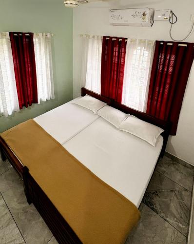 a bed in a room with red curtains at Olive Homestay in Cochin