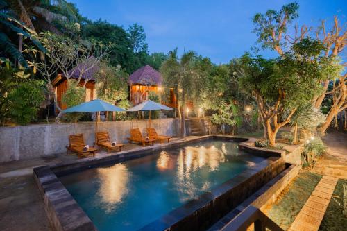 a pool with chairs and umbrellas in a backyard at Kamasan Nusa Penida By Reccoma in Nusa Penida