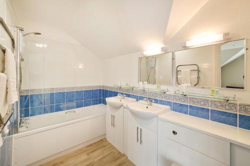 a bathroom with two sinks and a tub and a mirror at The Atherstone Red Lion Hotel in Atherstone