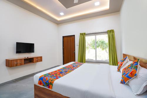 a bedroom with a bed and a tv on a wall at FabHotel Nakshtra Resort in Tāsgaon