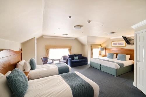 a hotel room with two beds and a couch at The Atherstone Red Lion Hotel in Atherstone