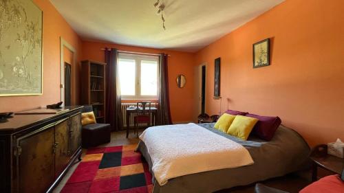 a bedroom with orange walls and a bed with yellow pillows at Villa Tronçais in Saint-Bonnet-Tronçais