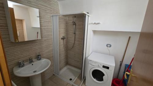 a bathroom with a shower and a sink and a washing machine at Casa Alba in Bernalda