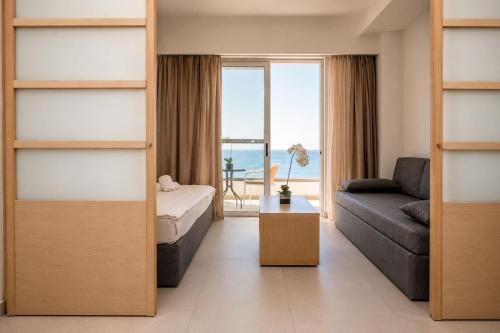 a bedroom with a bed and a couch and a view of the ocean at Kamari Beach in Lartos