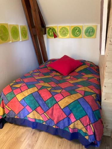 a bedroom with a colorful quilt on a bed at Studio à la Ferme in Limpiville