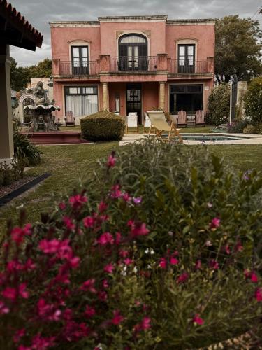 a house with pink flowers in front of it at Hotel Draghi in San Antonio de Areco