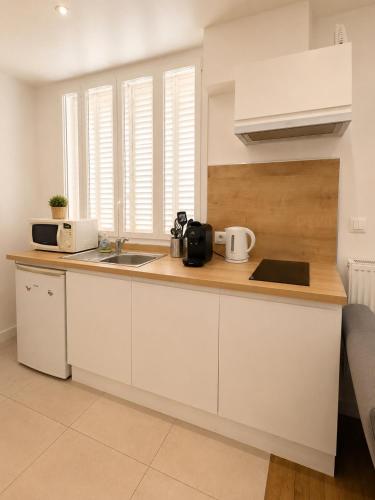 a kitchen with white cabinets and a sink at Centre ville - Houilles A1 in Houilles