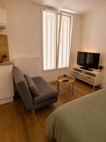 a living room with a couch and a tv at Centre ville - Houilles A1 in Houilles