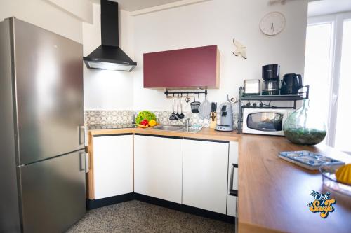 a kitchen with white cabinets and a stainless steel refrigerator at Le Petit Noirda in Audresselles