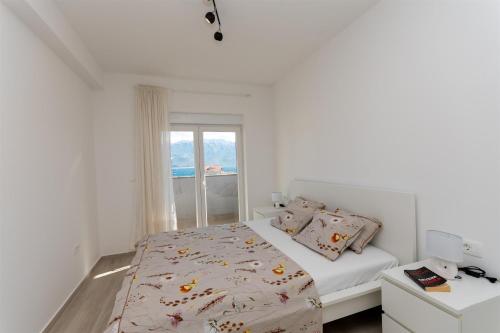a white bedroom with a bed and a window at Apartment Sankovic in Ražanac