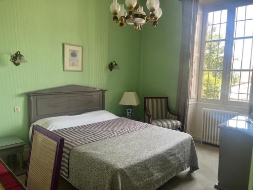 a green bedroom with a bed and a chandelier at Hôtel Chandouineau in Redon