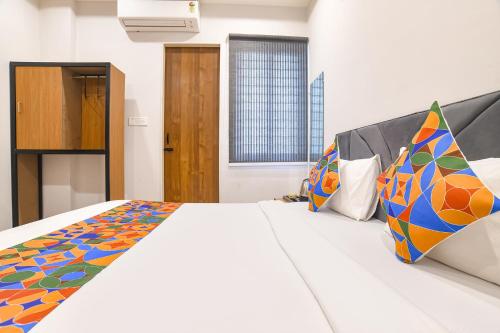 a bedroom with a large bed with colorful pillows at FabHotel Trivana, Mahalaxmi Nagar in Indore