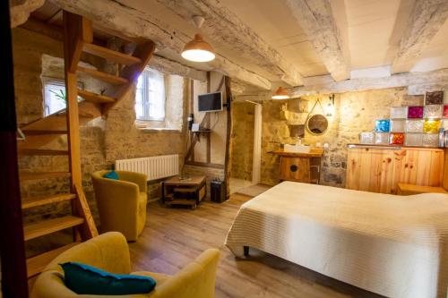 a bedroom with a bed and chairs in a room at Le gentil coquelicot in Saint-Pompont