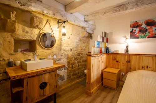 a bathroom with a sink and a stone wall at Le gentil coquelicot in Saint-Pompont
