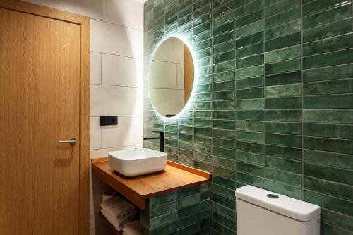 a green tiled bathroom with a sink and a mirror at Hotel Bon Repos in Calella