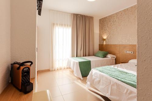 a hotel room with two beds and a window at Hotel Bon Repos in Calella