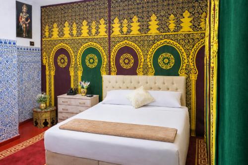 a bedroom with a bed with a gold headboard at Riad Imperial Atlas in Meknès