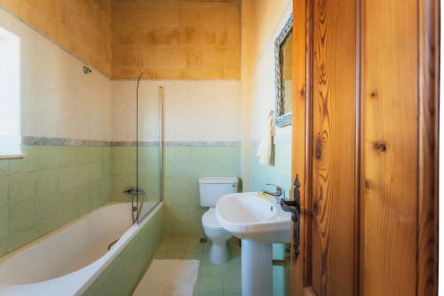 a bathroom with a sink and a tub and a toilet at Authentic Xagħra Farmhouse with Private Pool in Xagħra