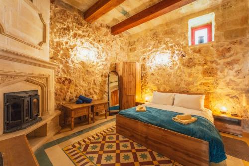 a bedroom with a bed and a fireplace at Authentic Xagħra Farmhouse with Private Pool in Xagħra
