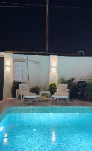 a swimming pool with two lounge chairs and a pool at Palm Villa in Mərdəkan