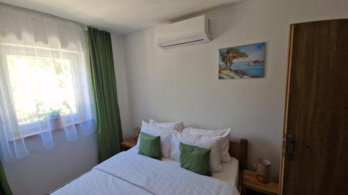 a bedroom with a bed with green curtains and a window at 4Rest Villa in Novalja