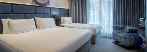 a hotel room with two beds and a chair at The Residence Hotel in Galway