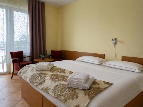 a bedroom with a large bed with towels on it at Hotel Zátoka in Senec