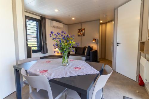 a dining room table with a vase of flowers on it at Delya, chalet confort, climatisation, piscine in Agde