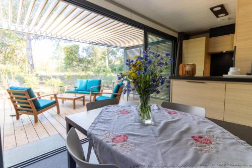 a kitchen with a table with a vase of flowers on it at Delya, chalet confort, climatisation, piscine in Agde