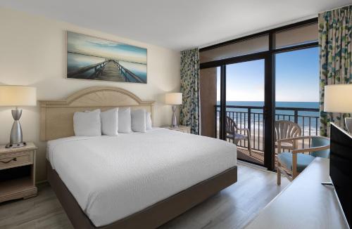a bedroom with a bed and a balcony at Beach Cove Resort in Myrtle Beach