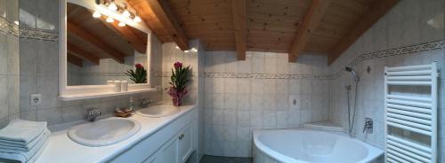 a bathroom with two sinks and a mirror and a tub at Wellnessappartements Margit in Alpbach