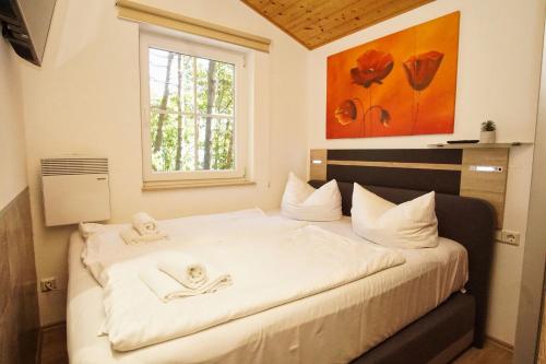 a bedroom with a large white bed with a window at Chalet Ostsee Nr 72 in Göhren