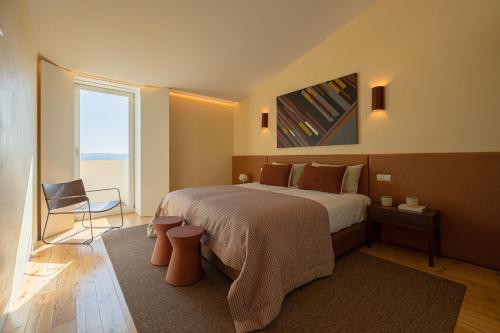 a bedroom with a bed and a chair and a window at Casas da Quinta de Santa Cruz - Douro Land in Peso da Régua
