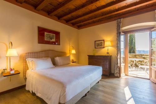 a bedroom with a large bed and a balcony at QC Grand Hotel Villa Arzaga Garda Spa & Golf in Calvagese della Riviera