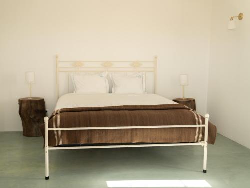 a bedroom with a bed with two tables and two lamps at Change The World - Herdade Monte do Peral in Montes Juntos