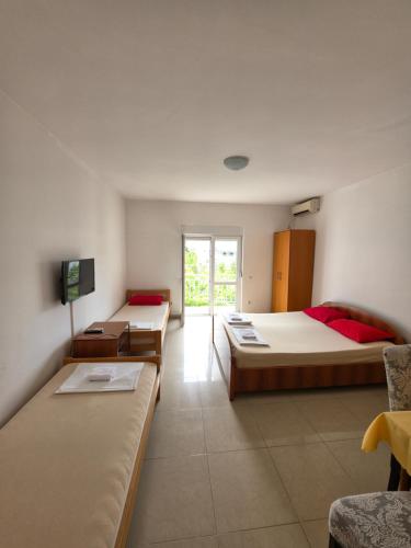 a hotel room with three beds and a tv at Apartmani Viki in Sutomore