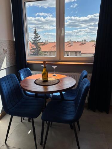 a dining room table with blue chairs and a window at Apartament Nova Starówka 2 in Konin