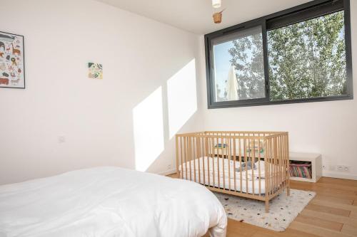 a bedroom with a crib and a large window at La Forge de Fiac - Grande maison de charme avec vue campagne in Fiac
