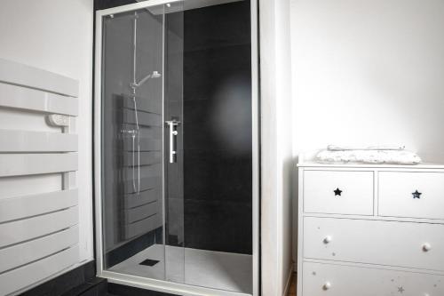 a shower with a glass door next to a dresser at La Forge de Fiac - Grande maison de charme avec vue campagne in Fiac