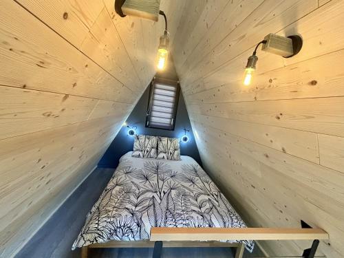 a bed in a small room with wooden walls at Tiny house au coeur de la nature in Touët-sur-Var