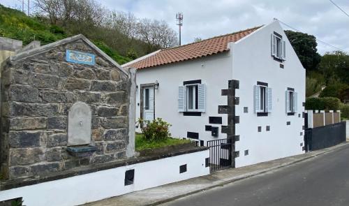 a white house with a stone wall next to a street at Angelic Sea View in Bretanha
