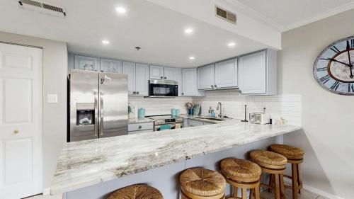a kitchen with a counter with stools and a refrigerator at Ocean Block retreat with easy beach access & shared pools in Ocean City