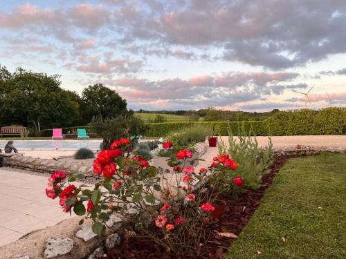 a garden with red flowers and a pond at Maison M in Surin