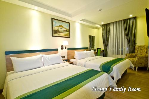 una habitación de hotel con 2 camas y una silla en Green Batara Hotel, en Bandung