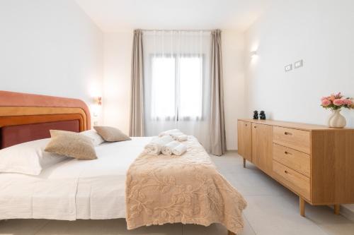 a bedroom with a bed and a dresser and a window at Domus Luxi in Teulada