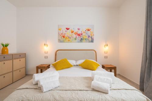 a bedroom with a bed with yellow pillows and a painting at Domus Soli in Teulada