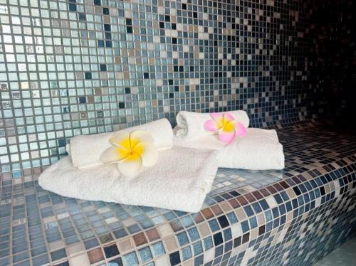 two towels with plumeriaeriaeria flowers on top of them at Chalet 23 Widemouth Bay in Bude