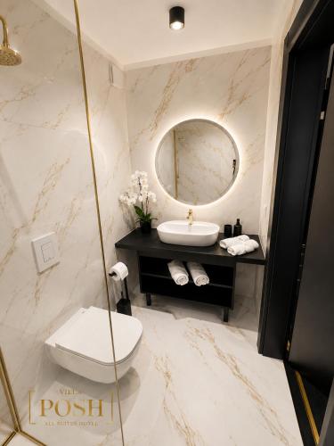 a bathroom with a sink and a toilet and a mirror at Villa Posh All Suites Hotel & SPA in Międzywodzie