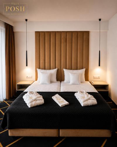 a bedroom with a large bed with two towels on it at Villa Posh All Suites Hotel & SPA in Międzywodzie
