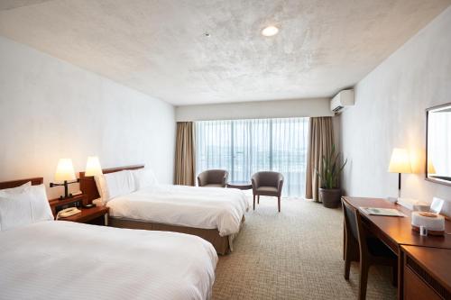 a hotel room with two beds and a desk at EM Wellness Kurashinohakko Lifestyle Resort in Kitanakagusuku